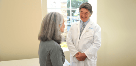 Doctor smiling at a patient in an exam room.