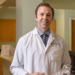 Photo of a doctor smiling holding a medical model of a foot and ankle