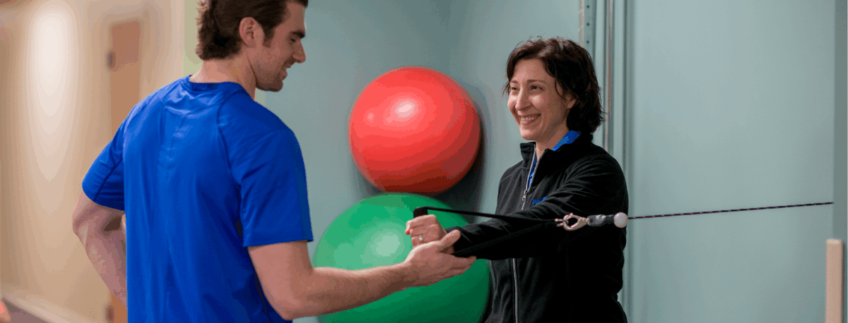 Two people standing in a physical therapy exercise room.