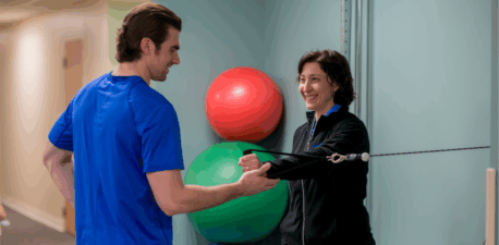 Two people standing in a physical therapy exercise room.