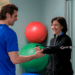 Two people standing in a physical therapy exercise room.