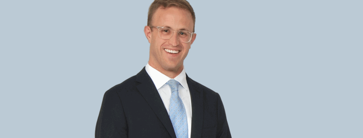 A man standing in a suit and tie smiling.