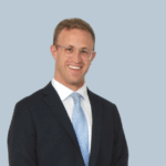 A man standing in a suit and tie smiling.