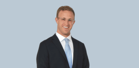 A man standing in a suit and tie smiling.